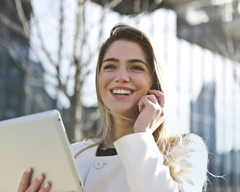 Business woman smiling and talking on the phone while holding a tablet