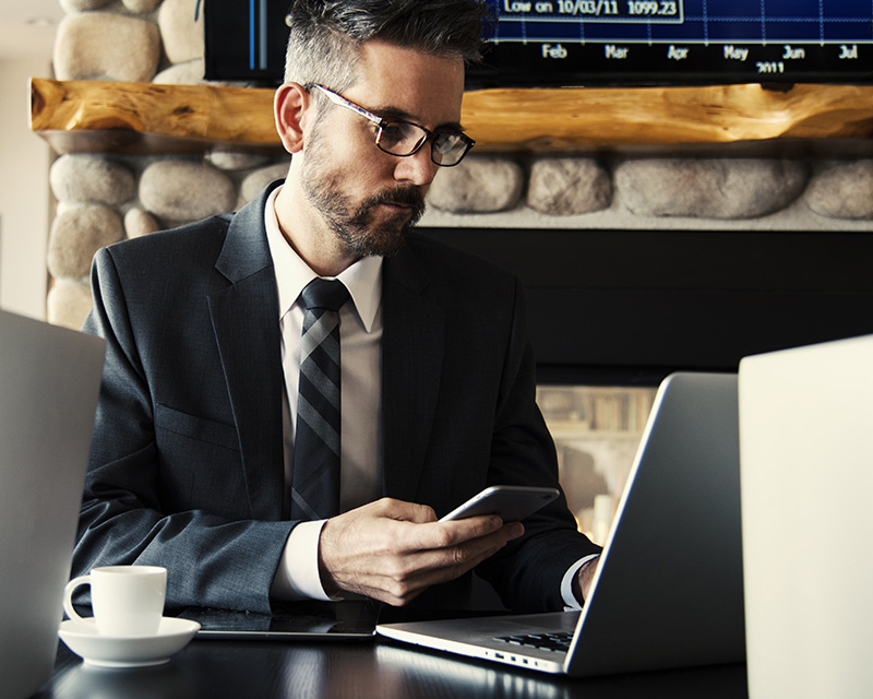 Businessman using laptop and cell phone in a coffee shop